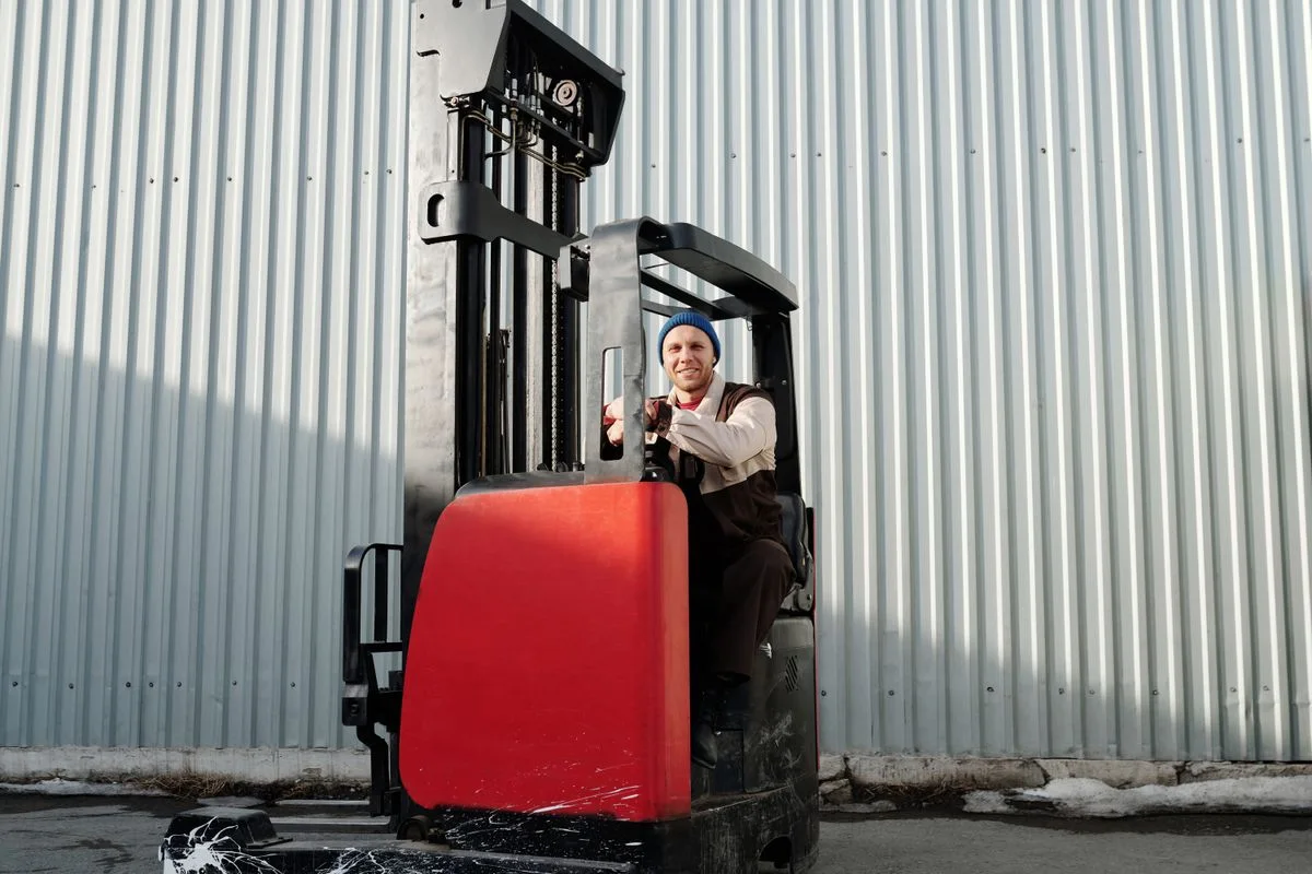 Forklift operator working outside an industrial warehouse